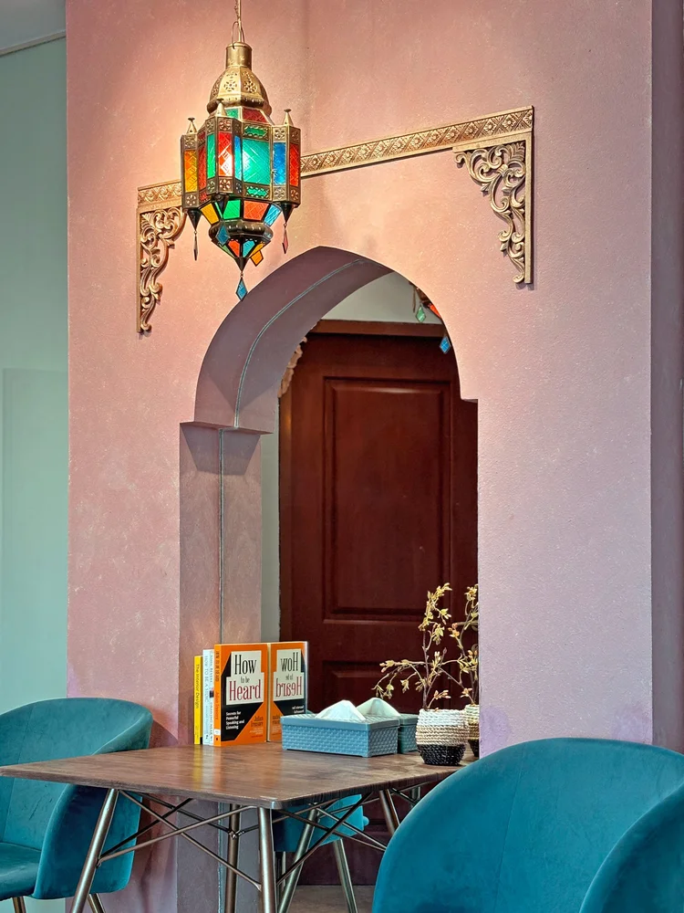 Marrakech: Lengkung ala Maroko dengan lentera kaca warna, meja makan dua orang di bawahnya.
