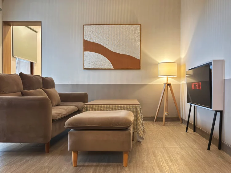 Seoul: Ruang keluarga bertema K-Drama Set: sofa cokelat, ottoman, dan TV dengan Netflix.
