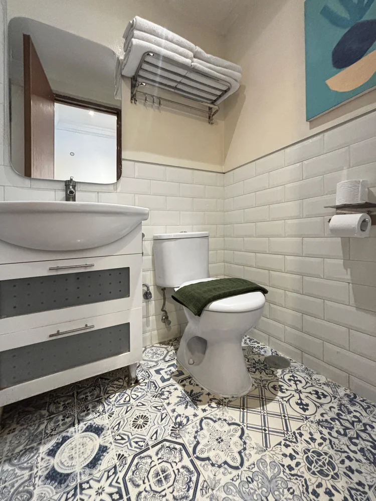 Santorini: Kamar mandi dengan wastafel, toilet, dan lantai ubin bermotif; sabun dan sampo sama di semua unit.
