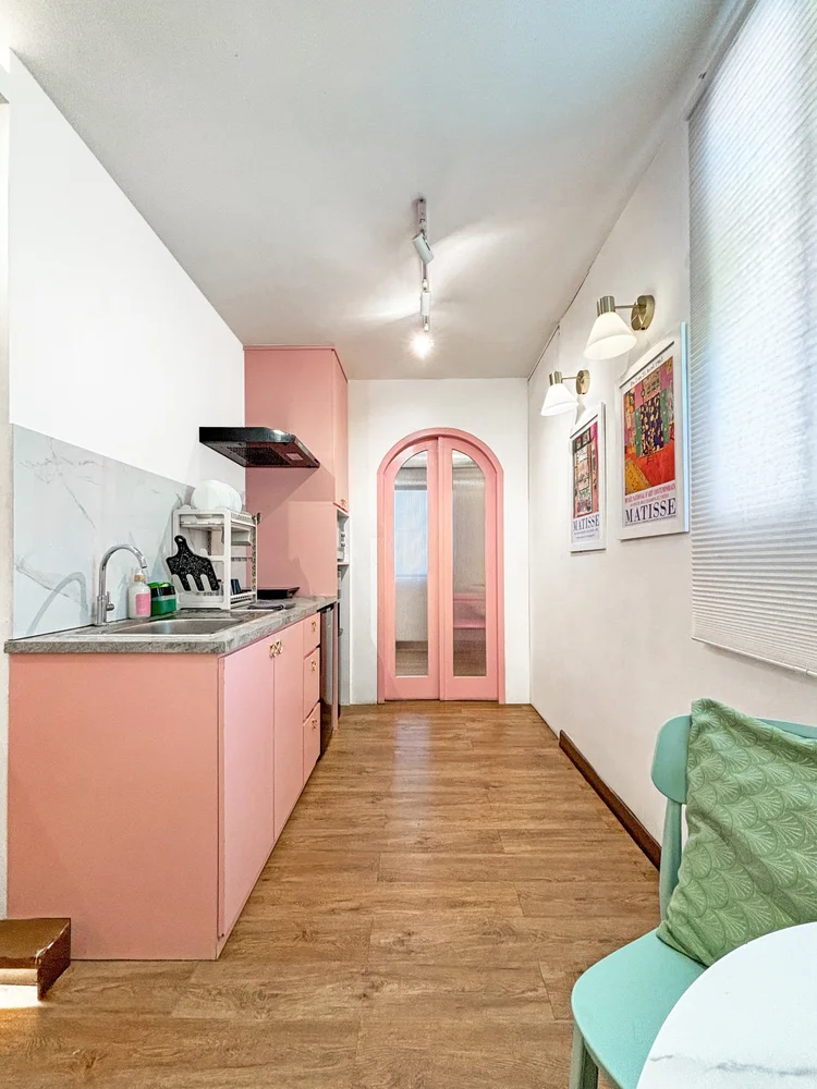 Milan: Dapur memanjang di lorong, pintu lengkung merah muda ke kamar tidur.
