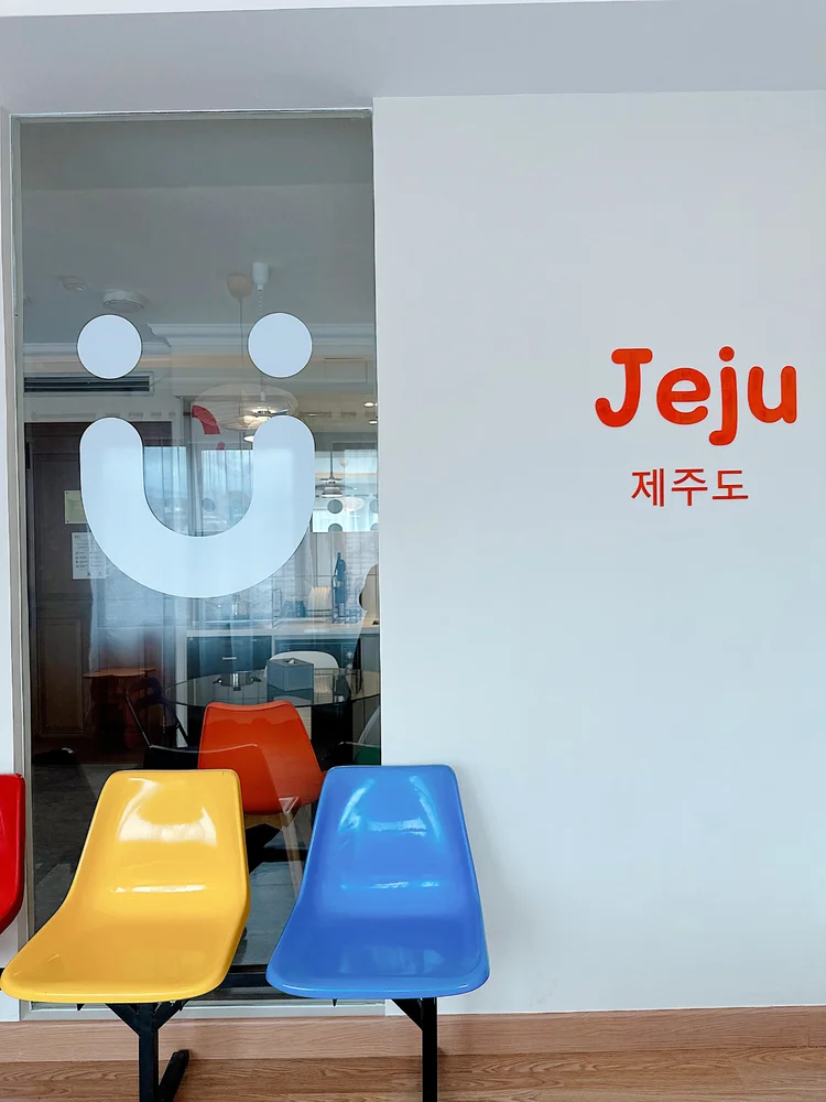 Jeju: Ada sudut dengan aksen dinding Jeju dan kursi warna-warni, kursi ekstra buat nongkrong.
