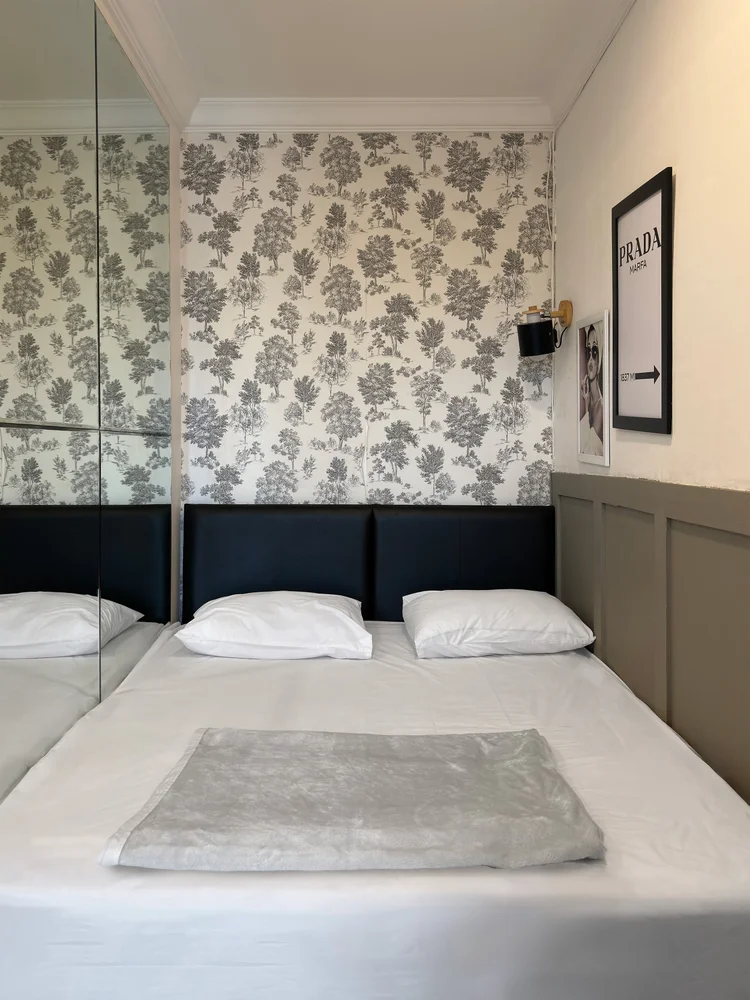 Florence: Kamar utama dengan wallpaper bermotif bunga dan sprei putih, standar yang sama di semua unit kami.