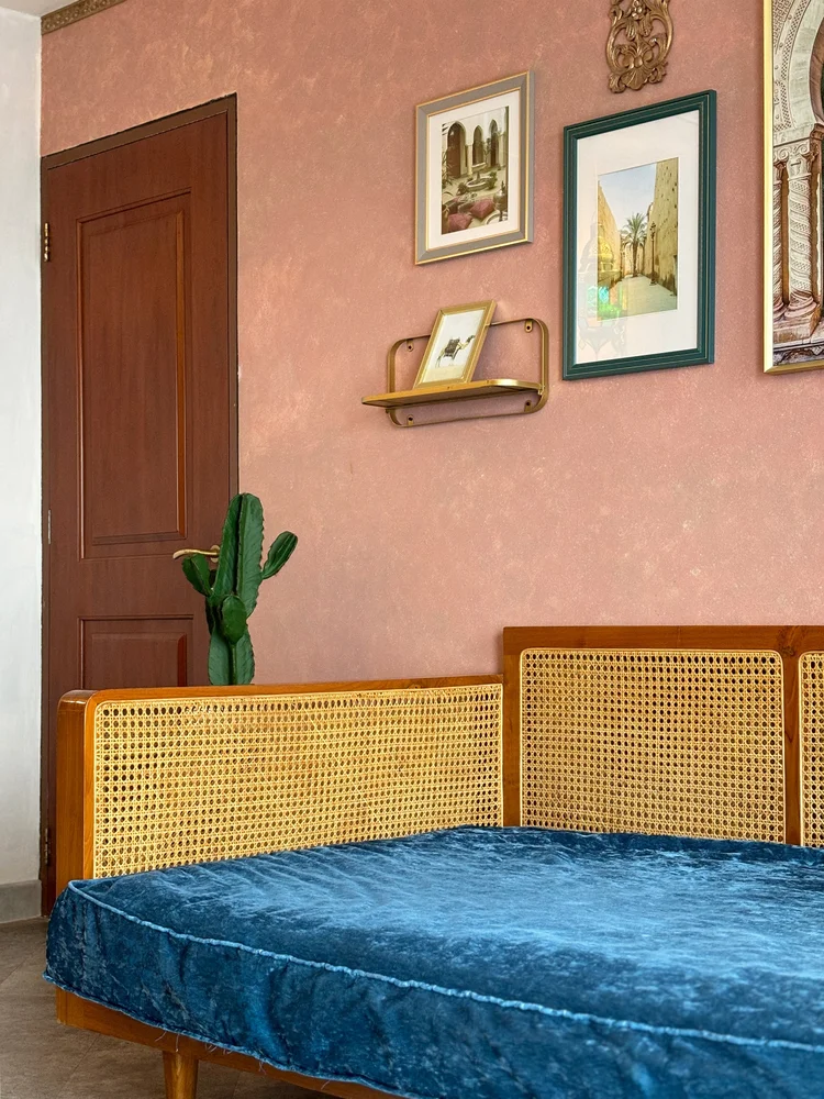 Marrakech: Sandaran rotan day bed, kaktus, dan bingkai di dinding merah muda.