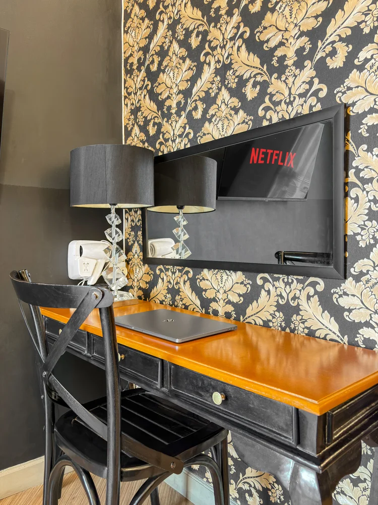 Vienna: Meja kerja dengan wallpaper damask emas-hitam, cermin TV Netflix, dan hair dryer.