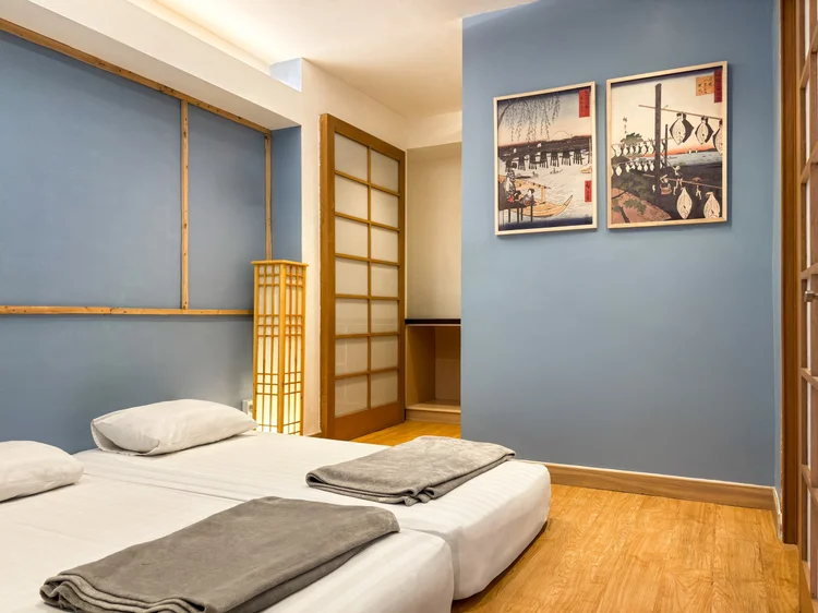 Yokohama: Kamar dengan dinding biru dan dua ranjang, sprei putih standar yang sama di semua unit kami.