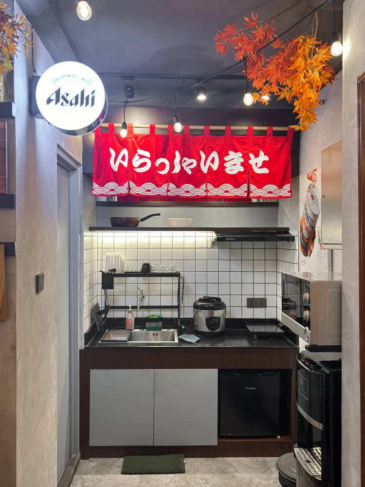 Shinjuku: Dapur terbuka dengan kompor induksi dan rice cooker, di bawah papan nama ala kedai Jepang.