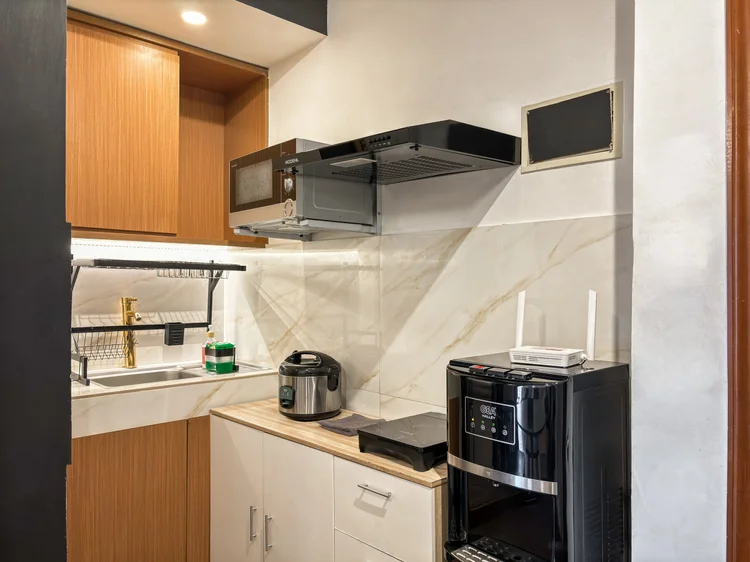 Vienna: Dapur terbuka dengan lemari kayu, microwave, dan wastafel; alat masak dasar sudah lengkap.