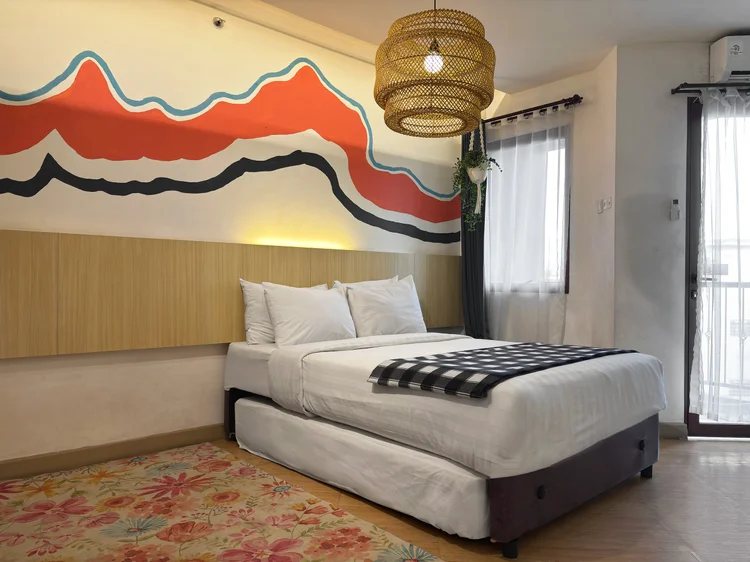 Barbados: Mural gunung di atas tempat tidur, dengan lampu rotan dan karpet bermotif.