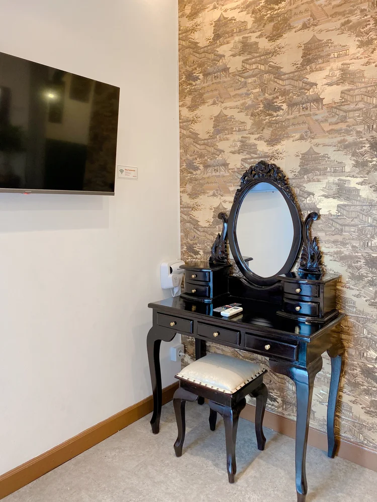 Saigon: Smart TV di dinding dan meja rias hitam berukir dengan cermin oval.