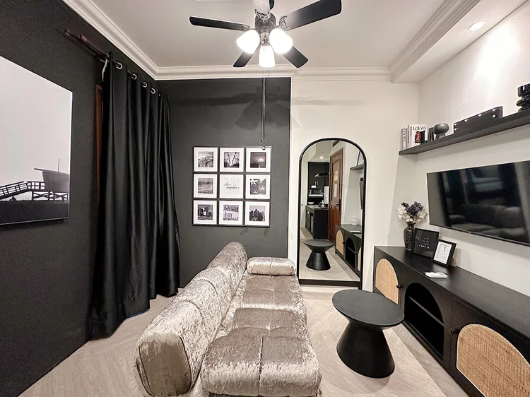 Los Angeles: Sofa beludru dan smart TV di ruang tamu, dengan cermin badan penuh di sampingnya.