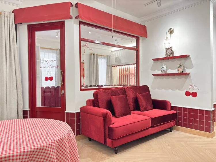 Chamonix: Ruang keluarga dengan sofa merah dan rak kecil bermotif ceri.