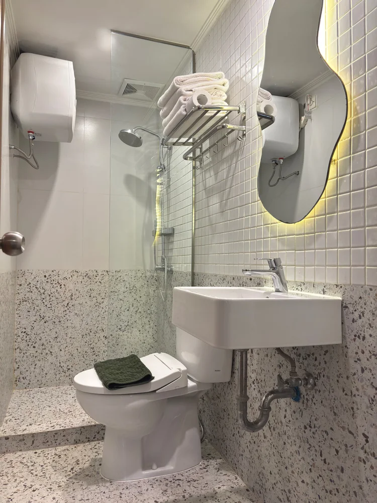 Seoul: Kamar mandi modern dengan lantai teraso, wastafel, dan toilet; sabun dan sampo sama di semua unit.