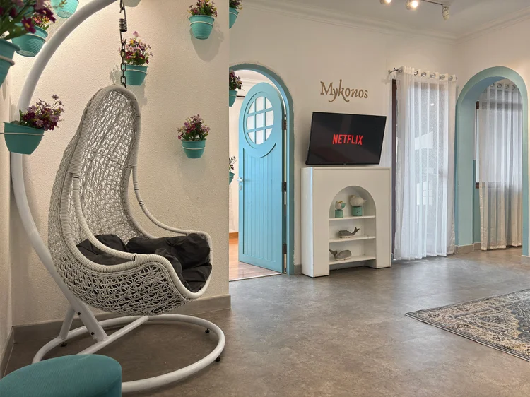 Mykonos: Kursi gantung rotan putih dekat pintu biru khas Mykonos.