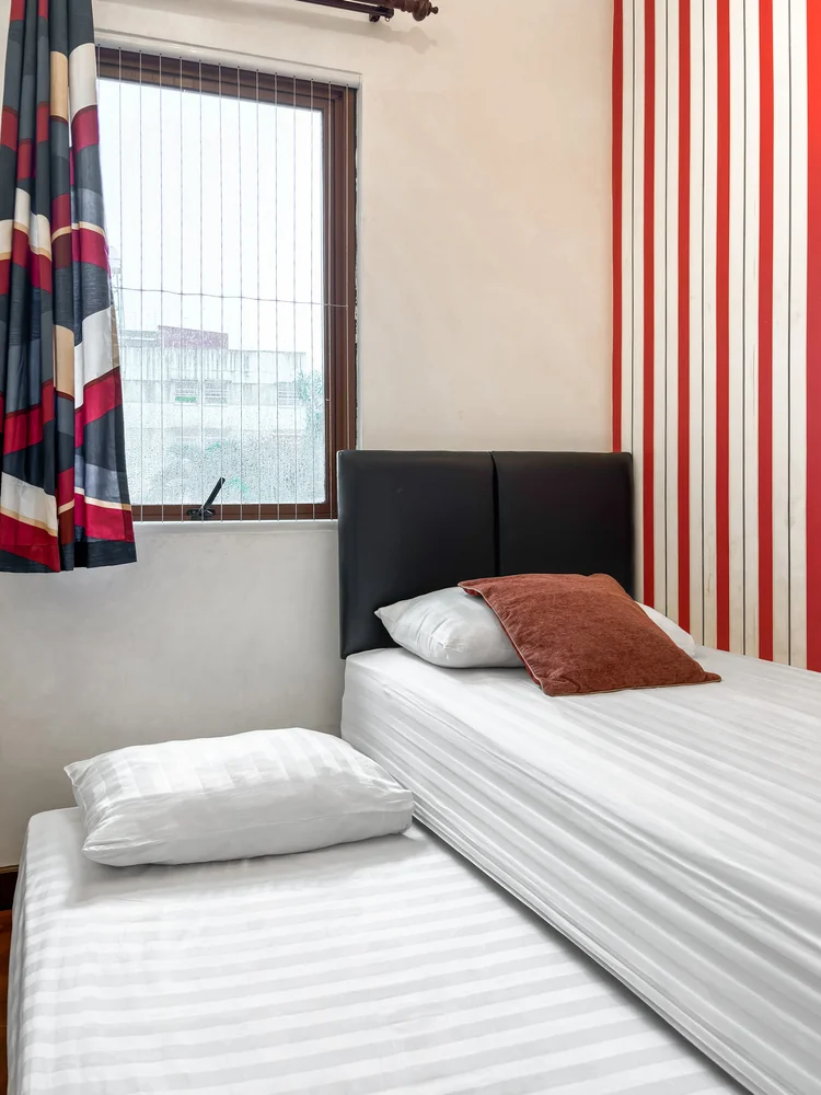 Amsterdam: Kasur single di dekat jendela, dengan tirai bermotif merah biru.
