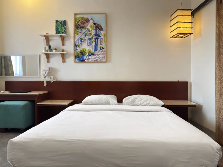 Santorini: Kamar dengan queen bed 160 cm, rak dinding, dan sprei putih standar semua unit kami.