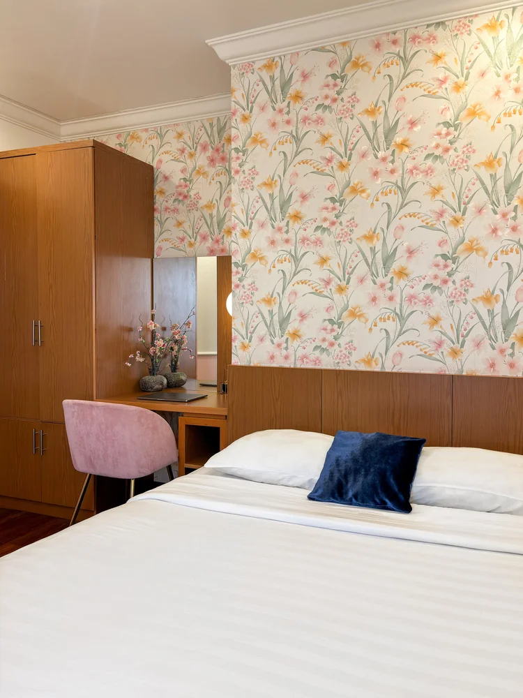 Salzburg: Kamar dengan wallpaper bunga, lemari pakaian, dan sprei putih standar semua unit kami.