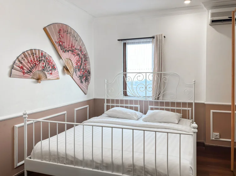Salzburg: Kamar dengan ranjang besi putih dan hiasan kipas di dinding, AC sendiri.