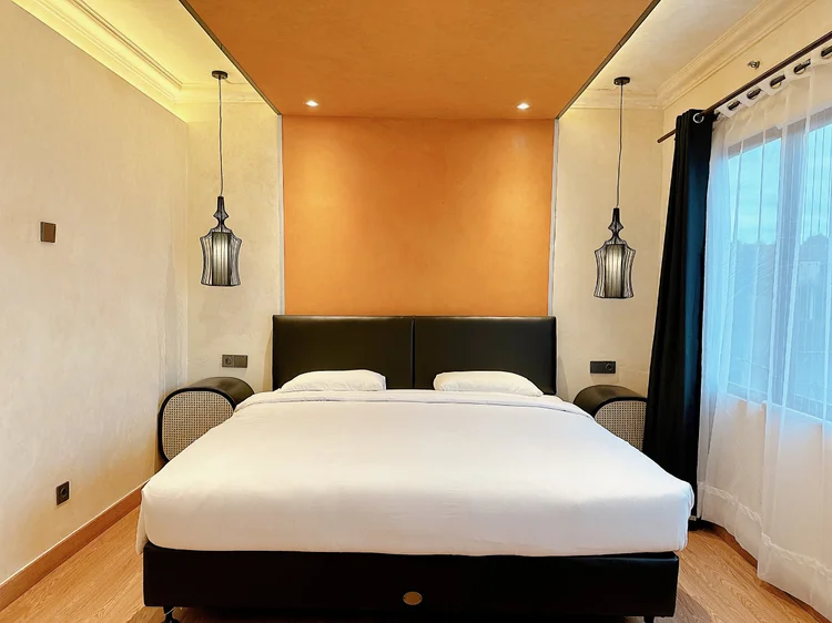 Melbourne: King bed 200x200 cm menghadap jendela bertirai, lampu gantung di kedua sisi.
