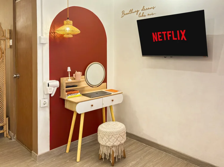 Ankara: Meja rias dengan cermin bulat, dan TV dengan Netflix di dinding.