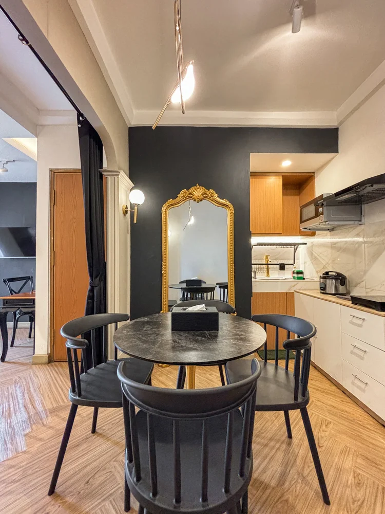 Vienna: Meja makan bundar dengan cermin berbingkai emas, dapur terbuka di baliknya.