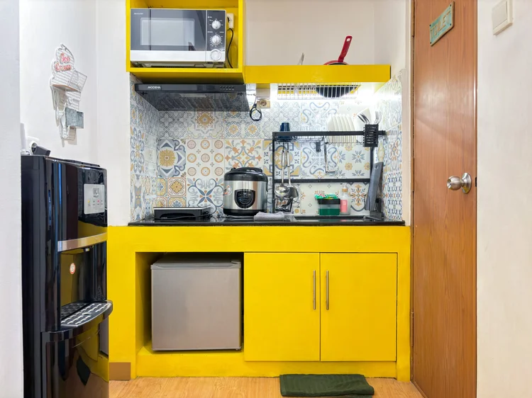 St. Tropez: Dapur terbuka: kompor induksi, microwave, rice cooker, kulkas, dan dispenser dengan galon cadangan.