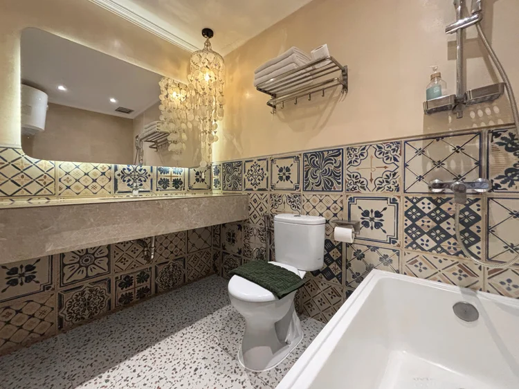 Santorini: Kamar mandi dalam kamar utama dengan bathtub dan ubin bermotif biru putih.