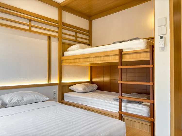 Omotesando: Tempat tidur susun 90 cm di samping kasur lantai; sprei putih seperti di semua unit kami.