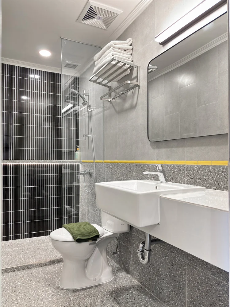 Dae Jeon: Kamar mandi dengan garis kuning ala peron, dan shower air hangat.