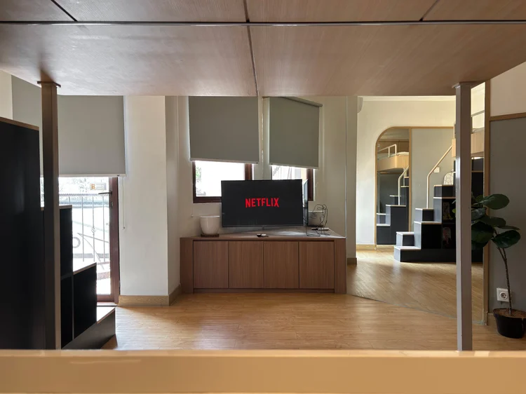 Den Haag: Smart TV dengan Netflix di atas lemari, menghadap sofa di bawah loft bed.