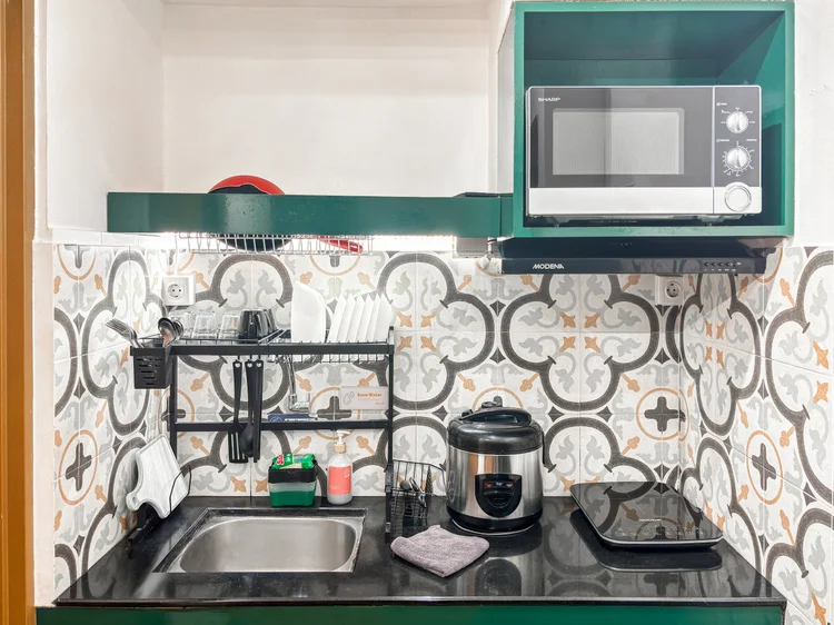 Tanzania: Dapur terbuka dengan wastafel, microwave, dan rice cooker; alat masak dasar sudah lengkap.