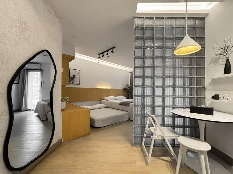 Sydney: Cermin tinggi berlekuk, area tidur dan meja makan dalam ruang yang sama.