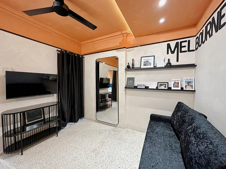 Melbourne: Ruang keluarga: sofa beludru hitam, smart TV, dan kipas langit-langit.