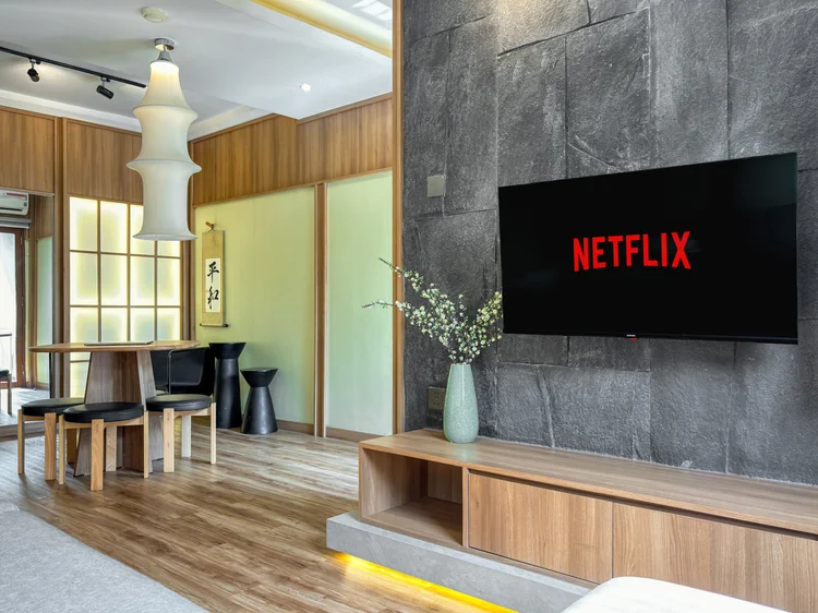 Sapporo: Smart TV dengan Netflix di dinding batu, panel shoji menyala lembut di sampingnya.