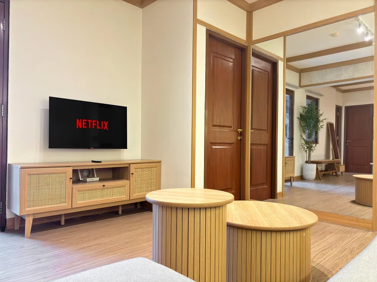 Nara: TV dengan Netflix di atas kredensa rotan, menghadap sofa.