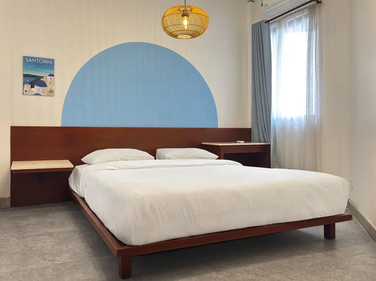 Santorini: Kamar dengan queen bed di atas dipan kayu dan lengkungan biru di dinding.