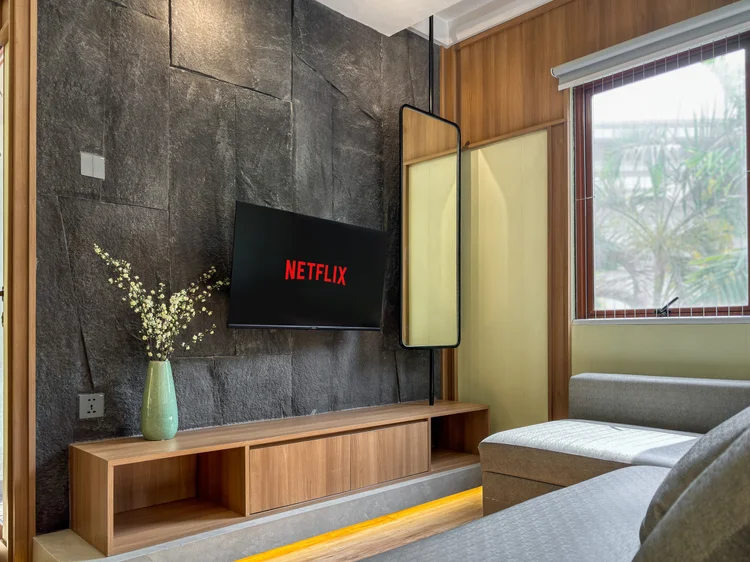 Sapporo: TV dengan Netflix menghadap sofa dan area tidur, cermin tinggi di sisinya.