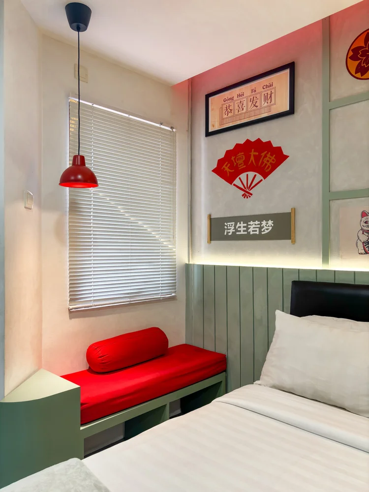 Hong Kong: Kasur tarik di dekat jendela, dengan bangku merah kecil di sisinya.