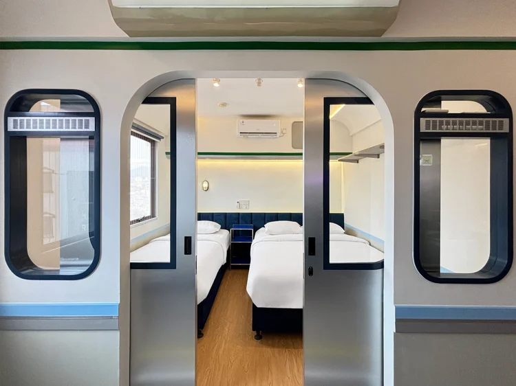 Dae Jeon: Pintu geser membuka ke kamar tidur dengan dua kasur bertepi biru.