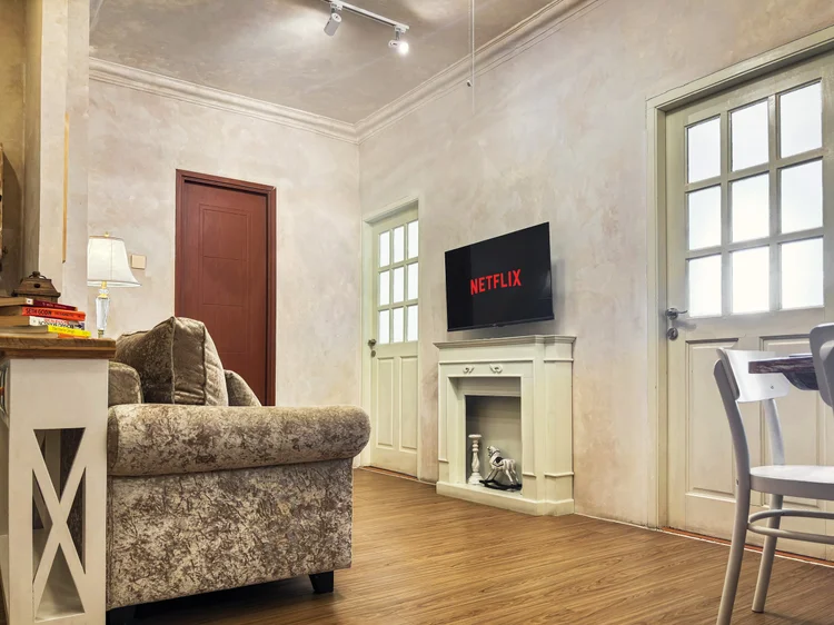 Bordeaux: Sofa tiga dudukan menghadap smart TV dengan Netflix, kipas langit-langit di atasnya.
