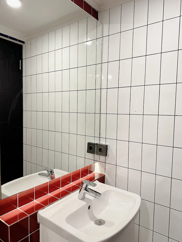 Berlin: Wastafel dengan cermin, ubin putih bergaris hitam ala Bauhaus.